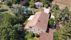 Una casa con techo de tejas, rodeada de árboles y una piscina.