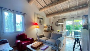 Una sala de estar acogedora con un sillón rojo, un sofá gris, una mesa de centro de madera y una lámpara.