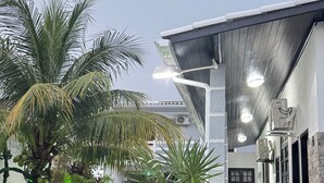 Uma área de piscina com uma casa moderna, palmeiras e um jardim.