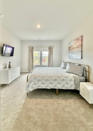 A bedroom with a bed, a TV, a dresser, and a window with curtains. - NEW! Sweet Tee Beach Escape (Little River)