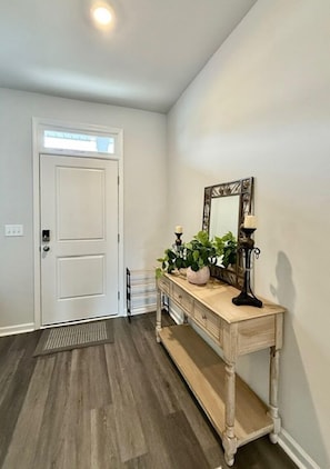 A hallway with a white door, a wooden console table with a mirror, and a potted plant. - NEW! Sweet Tee Beach Escape (Little River)