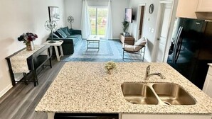 Una cocina moderna con encimera de granito, pileta de acero inoxidable y lavavajillas.