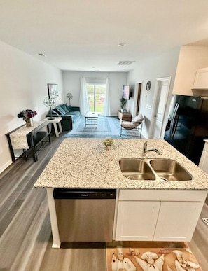 A modern kitchen with a granite countertop, stainless steel sink, and a dishwasher. - NEW! Sweet Tee Beach Escape (Little River)