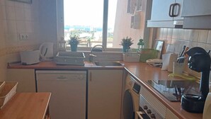 Une cuisine compacte équipée d’un lave-vaisselle, d’un lave-linge et d’une fenêtre donnant sur l’extérieur.