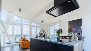 Et moderne køkken med en stor ø, mørke skabe og udsigt over byens skyline gennem vinduerne.