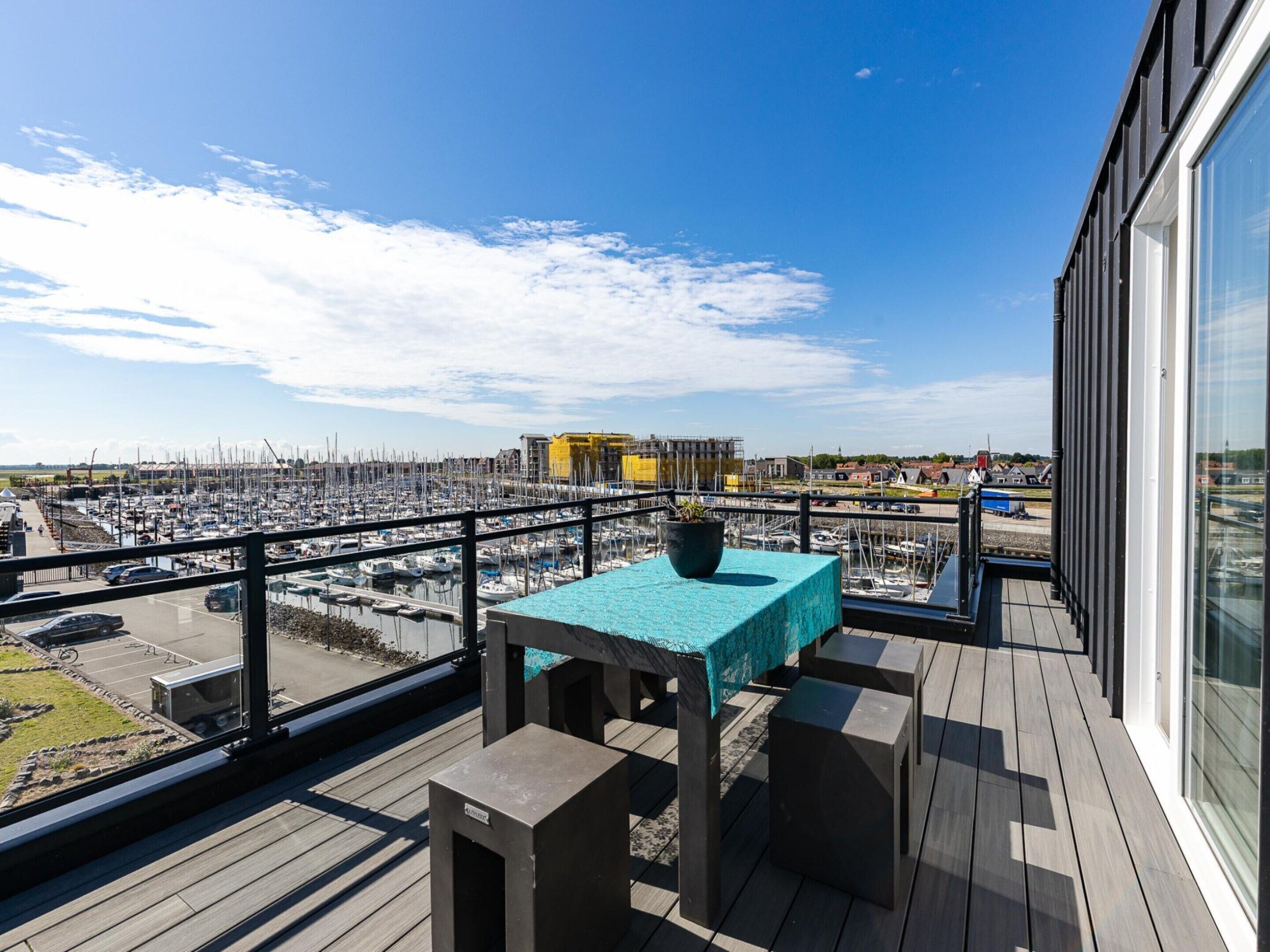 A balcony with a table and chairs, overlooking a marina with numerous boats.