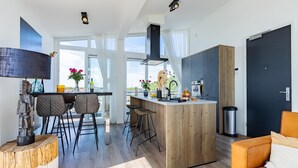 Et moderne køkken med en central ø, barstole, et spisebord og en sofa.