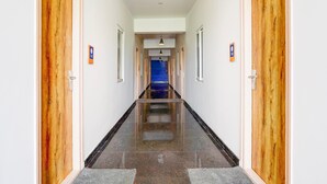 Un passadís amb portes de fusta, una porta blava al final i un paviment de rajoles.