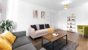 Un salon moderne avec un canapé, une table basse et un fauteuil vert.