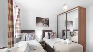Une chambre d’hôtel avec deux lits, un grand miroir, un tableau représentant un lion et un luminaire moderne.