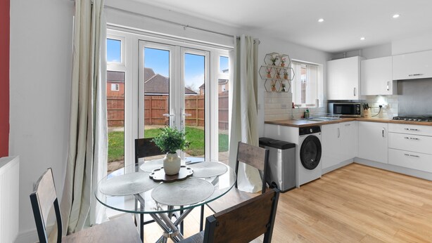 Une cuisine moderne avec des meubles blancs, un four à micro-ondes et un lave-linge.