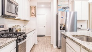 A modern kitchen with white cabinets, stainless steel appliances, and a granite countertop. - Woodridge (Porter)