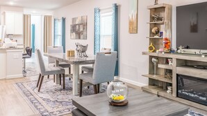 A modern living room with a dining area, a TV, and a fireplace. - Woodridge (Porter)