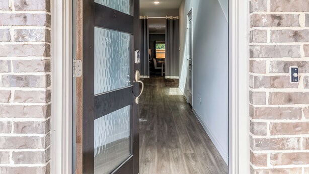 A hallway with brick walls, a wooden floor, and a door with frosted glass panels. - Woodridge (Porter)