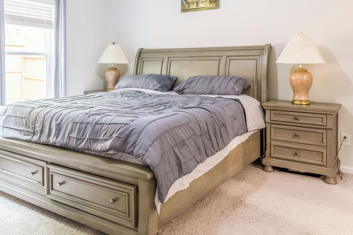 A bedroom with a bed, nightstands, and a painting on the wall.