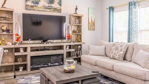 A modern living room with a flat-screen TV, wooden entertainment unit, beige sofa, and a coffee table. - Woodridge (Porter)