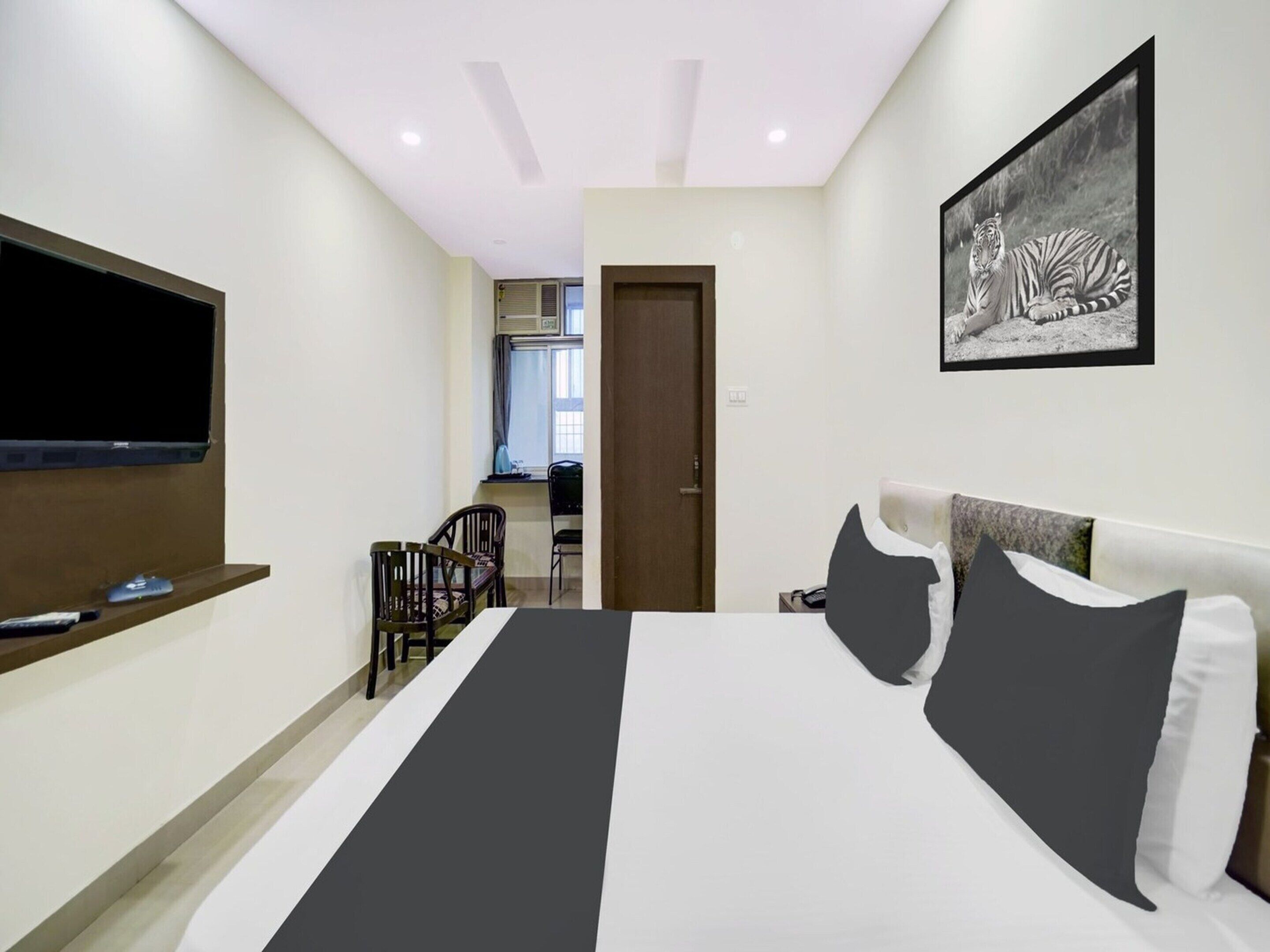 A bedroom with a bed, a TV, a desk, and a chair.