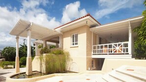 Ein modernes Haus mit überdachter Terrasse, Swimmingpool und gepflegtem Garten.