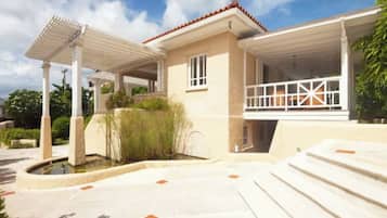 Une maison moderne dotée d’un patio couvert, d’une piscine et d’un jardin bien entretenu.