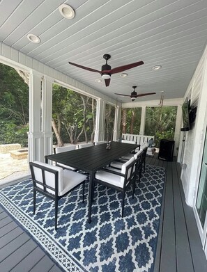A covered outdoor patio with a table and chairs, ceiling fans, and a patterned rug. - Beautiful house in Islamorada (Islamorada)