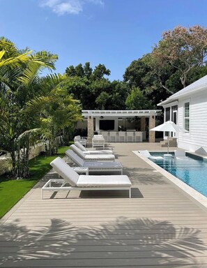 A poolside area with lounge chairs, a barbecue area, and a pool. - Beautiful house in Islamorada (Islamorada)