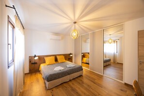 A bedroom with a large bed, a bedside table, a mirror, and a ceiling light fixture.