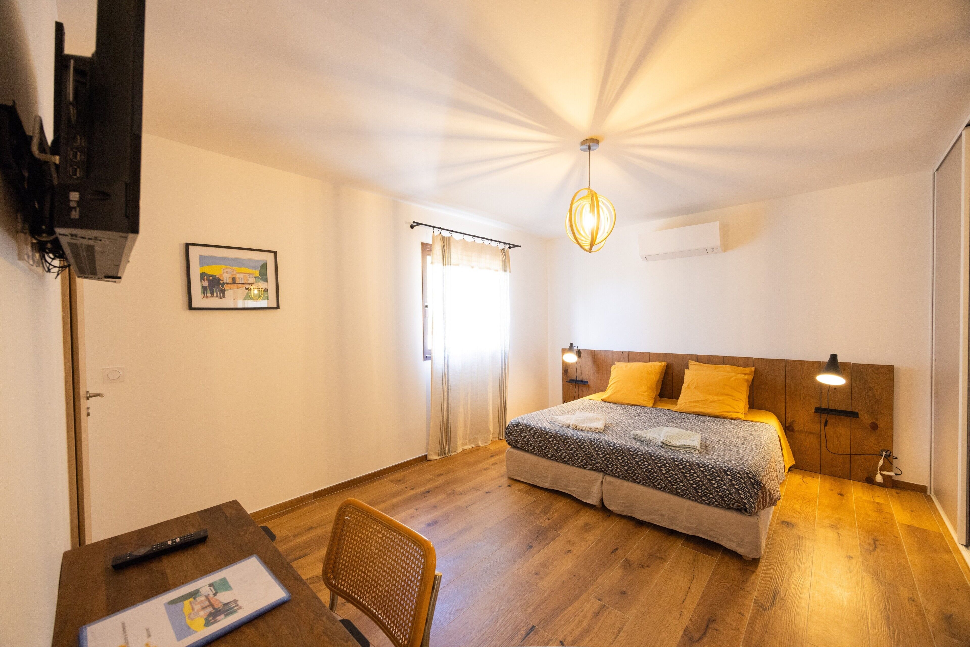 Een slaapkamer met een bed, bedlampen, een bureau en een stoel.