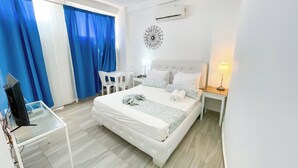 Hotellihuone, jossa on sänky, työpöytä, tuoli, televisio ja ilmastointilaite.