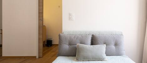 A bedroom with a bed, a door, and a light switch on the wall.