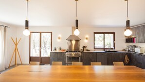 Une cuisine moderne dotée d’un îlot central, de luminaires suspendus et d’une grande table à manger.