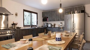 Una cocina moderna con una mesa de comedor para dos personas, equipada con estufa, horno y refrigerador.