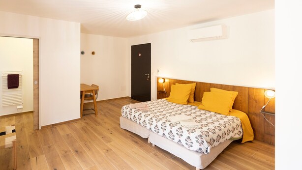 Un dormitorio con una cama de madera, una mesita de noche, una silla y una puerta.