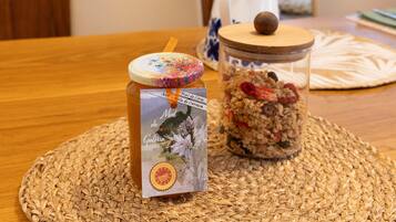 Un bocal de granola avec un couvercle en bois et une étiquette, posé sur un set de table en fibres naturelles, lui-même placé sur une table en bois.