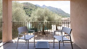 Un balcón con dos sillas y una mesa, con vistas a un paisaje montañoso.