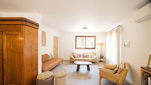 Una sala de estar con sofá, otomanas, una mesita de centro y un aparador de madera.