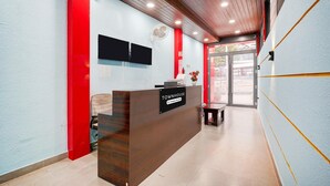 A reception desk with a sign reading 'TOWNHOUSE,' a flat-screen TV, and a fan on the wall. - Suite Indiranagar Jeevan Bhima Nagar (Bengaluru)