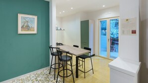 Un comedor con mesa y sillas, un cuadro enmarcado en la pared y vistas a través de un ventanal.