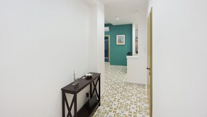 Un pasillo con un aparador oscuro, una puerta y una pared color aguamarina con un cuadro.