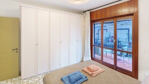 Un dormitorio con cama, armario, ventana con vistas al exterior y luz en el techo.