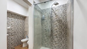 Een badkamer met douche, toilet en bidet.