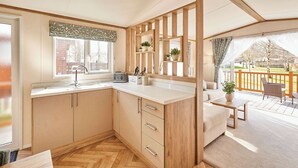 A kitchen with wooden cabinets, a sink, a window, and a view of the outdoors. - Host & Stay | Molly's Place (Morpeth)