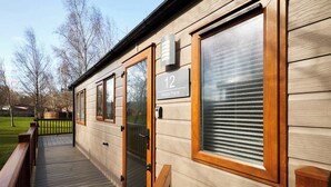 A wooden exterior of a building with a number '12' sign, a glass door, and a wooden deck. - Host & Stay | Molly's Place (Morpeth)