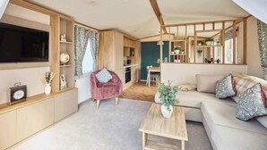 A modern living room with a sofa, a wooden coffee table, and a pink chair. - Host & Stay | Molly's Place (Morpeth)