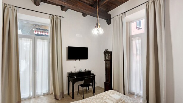 Une chambre à coucher avec un lit, un bureau, une télévision et une horloge.