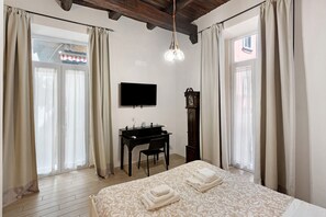 A bedroom with a bed, a desk, a TV, and a clock. - Teatro Nuovo Apartment Holiday Home with Balcony, Wi-Fi and Air Conditioning (Napoli)