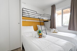 Ein Zimmer mit Etagenbetten, einer Hängetreppe, einem Kuscheltier und einem Fenster mit Vorhängen.