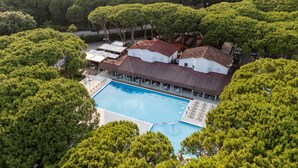 Ett flygbildsbild av ett semesterområde med en swimmingpool, omgivet av täta träd.