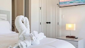 A hotel room with a neatly made bed, a wall-mounted TV, and a bedside table with a lamp and remote control. - Stay in Pure Luxury with Resort-Style Amenities! (New Braunfels)