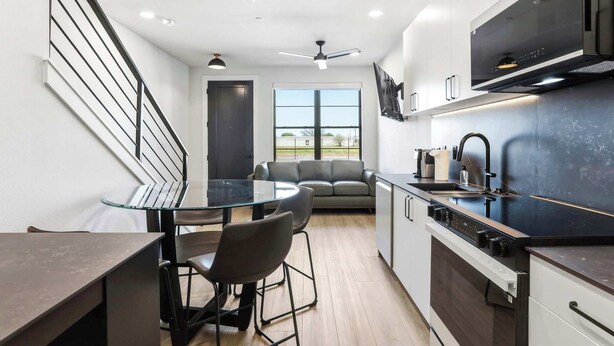 A modern kitchen with a dining area, a sofa, and a staircase. - Stay in Pure Luxury with Resort-Style Amenities! (New Braunfels)
