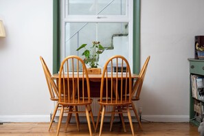 A dining area with a wooden table and chairs, a potted plant, and a window with a view. - Modern 2BDR Retreat | Near Beach & City Centre (Brighton and Hove)